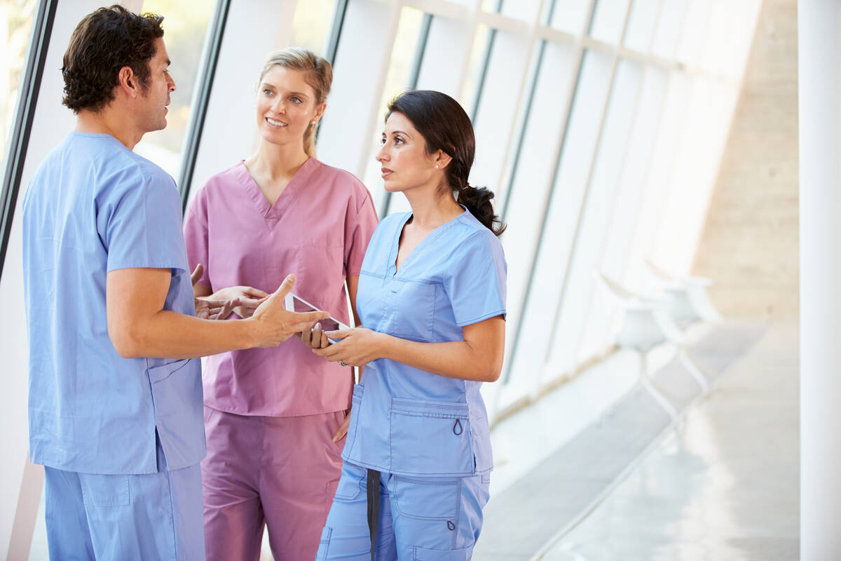 Mehrere Personen in Berufskleidung des Gesundheitswesens stehen in einer Klinik oder Gesundheitseinrichtung zusammen und tauschen sich aus. Das Bild symbolisiert die Diskussion um die Zukunft der Landespflegekammer Rheinland-Pfalz.